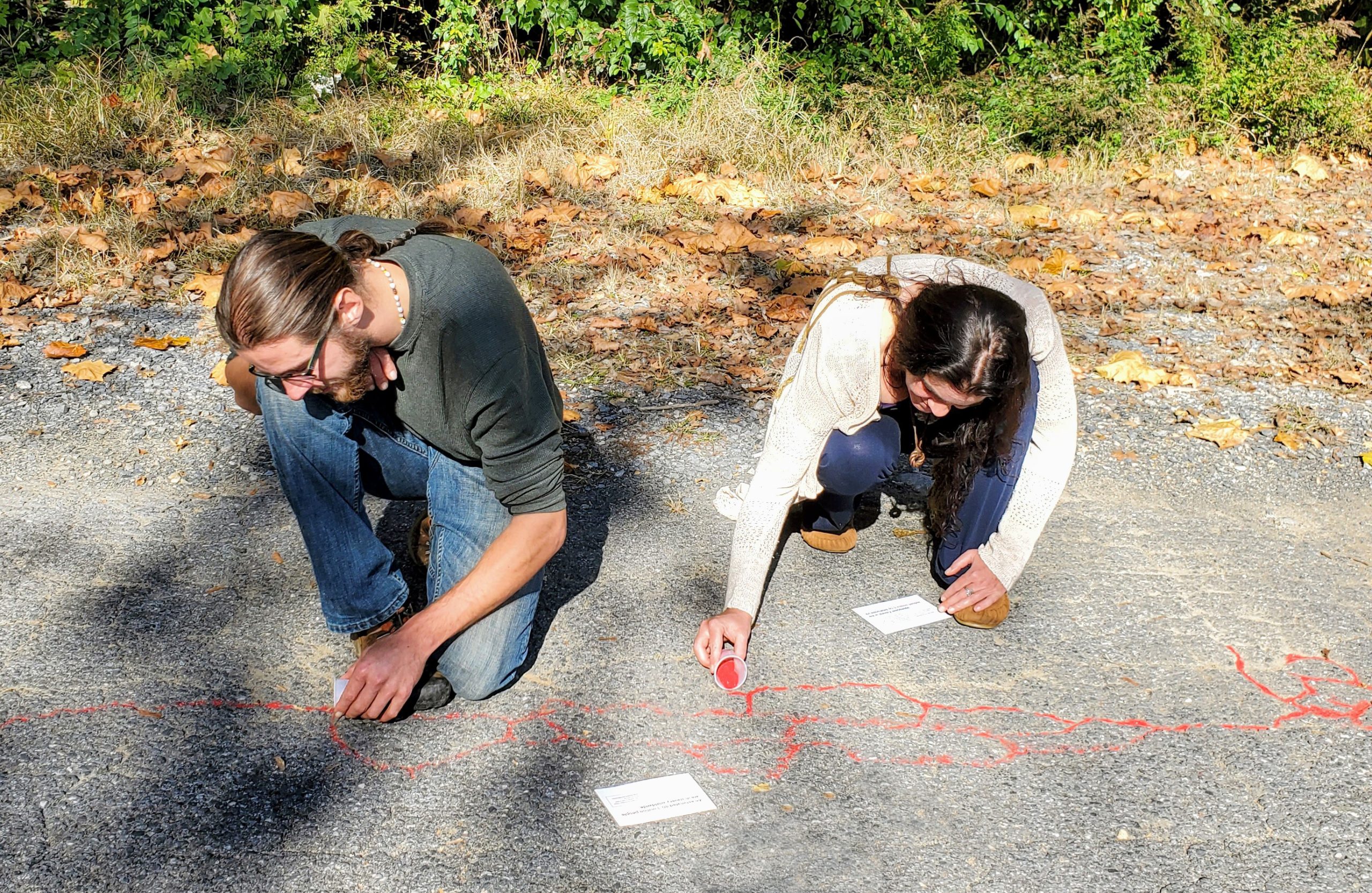 Red Sand Project sidewalk A man and a woman place red sand into cracks on the Karl Stirner Arts Trail in Easton, Pennsylvania, as part of the Red Sand Project.