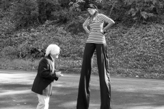 Someone dressed as an old man stands by a woman on stilts at the Come as You Art event on the Karl Stirner Arts Trail.