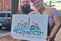 A man and woman together hold a Poetry in the Wild sign.