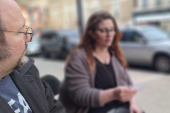 Lynn Alexander sits outside and reads a poem aloud as Darrell Parry listens.
