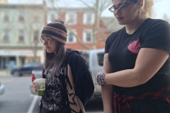 Two women stand and listen to poetry.