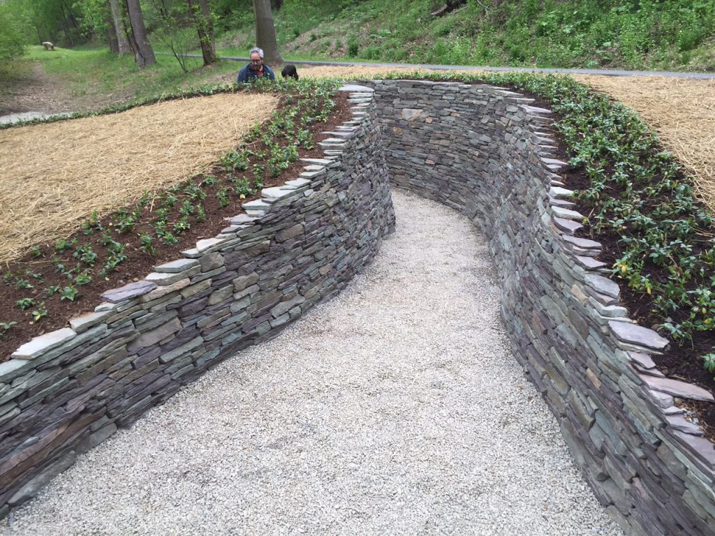 Water Way by Paul Deery on the Karl Stirner Arts Trail in Easton, Pennsylvania, features two parallel, curving stone walls around a walkway. 
