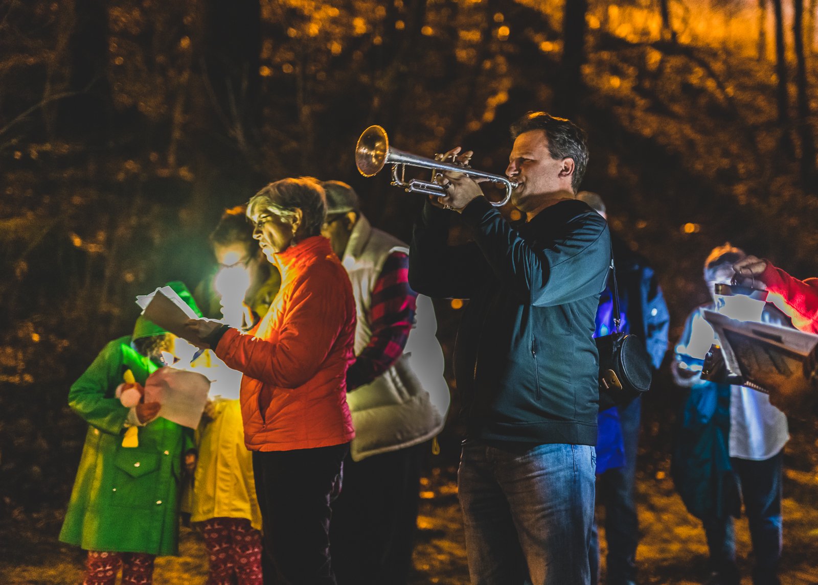 A man plays a trumpet while others hold papers with lyrics at a Winter Solstice event at the Karl Stirner Arts Trail in Easton, Pennsylvania.