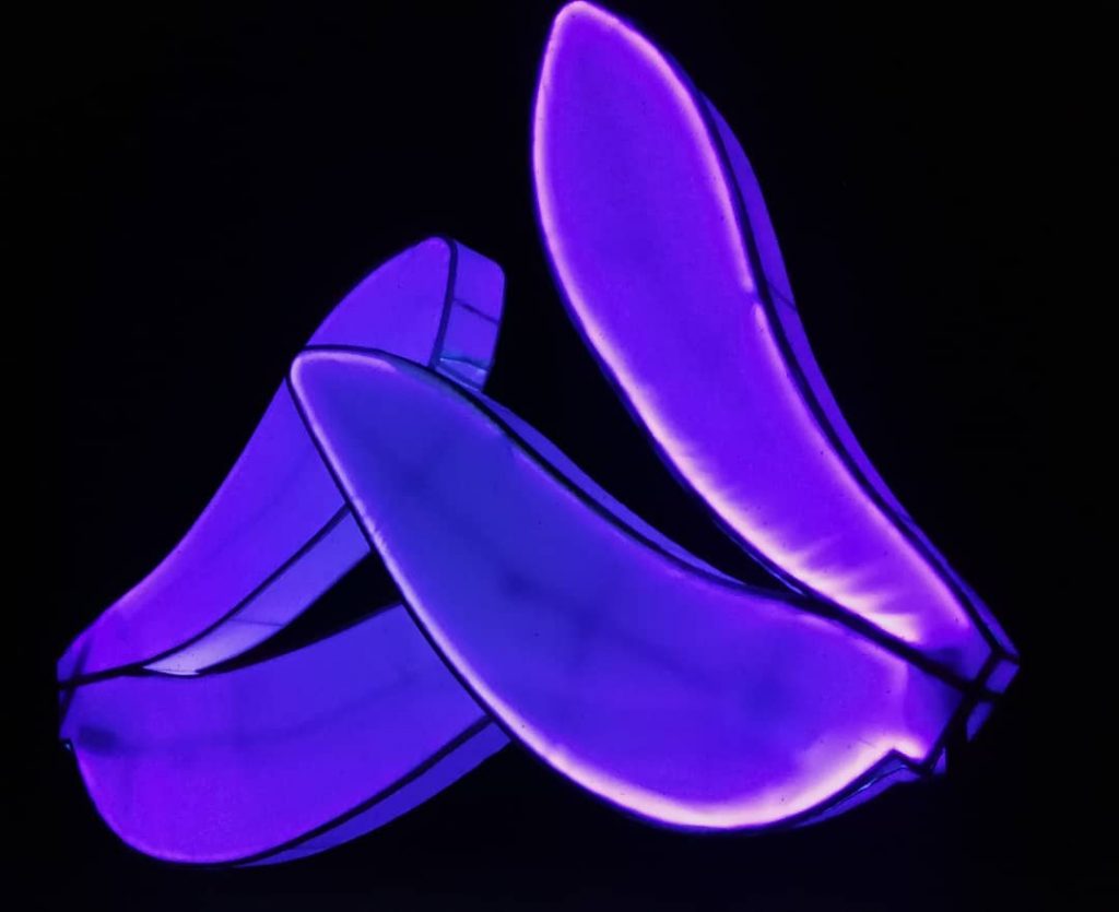 The lighted outdoor sculpture Love Motel for Insects has two shapes resembling two pairs of bug wings with purple lighting.