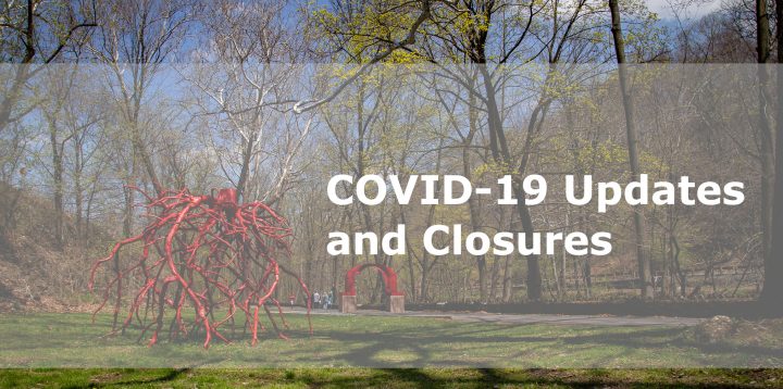 Trees, the walking patch, an artwork consisting of red tree roots, and the red arch sculpture on the Karl Stirner Arts Trail in Easton, Pennsylvania, along with the words COVID-19 Updates and Closures