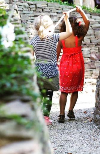 Two girls walk through a section of the Waterway artwork by Paul Deery, featuring walls of stone and natural and found materials, on the Karl Stirner Arts Trail in Easton, Pennsylvania.