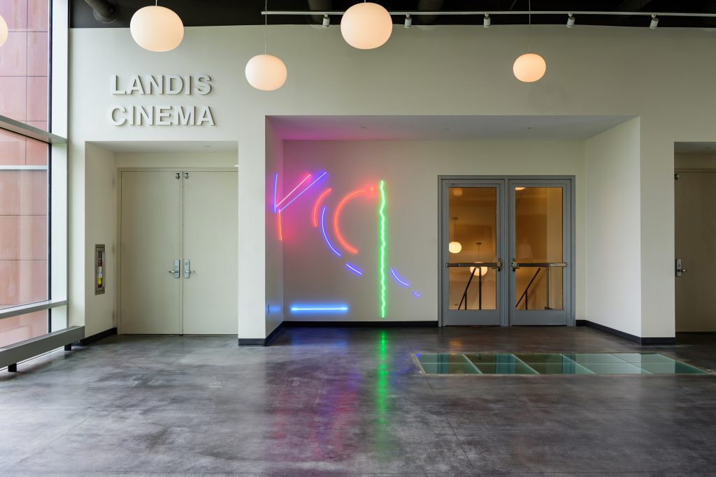The installation JT by Stephen Antonakos is comprised of neon tubes hanging on the wall near the entrance of Landis Cinema in Buck Hall on the Lafayette College campus.