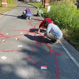 Community members place red sand and colored chalk on the pavement as part of the Red Sand Project on the Karl Stirner Arts Trail in Easton, Pennsylvania.