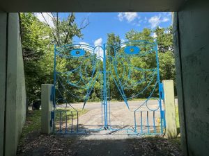 Willie Cole's blue Grace Gate depicts a face on the gate as it stands on a sunny day on the Karl Stirner Arts Trail in Easton, Pennsylvania.