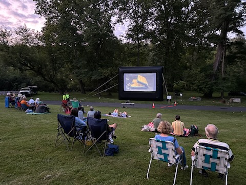 People sit in chairs and on the grass as they watch the film At Eternity's Gate during the Movies Along the Trail event on the Karl Stirner Arts Trail in Easton, Pennsylvania.