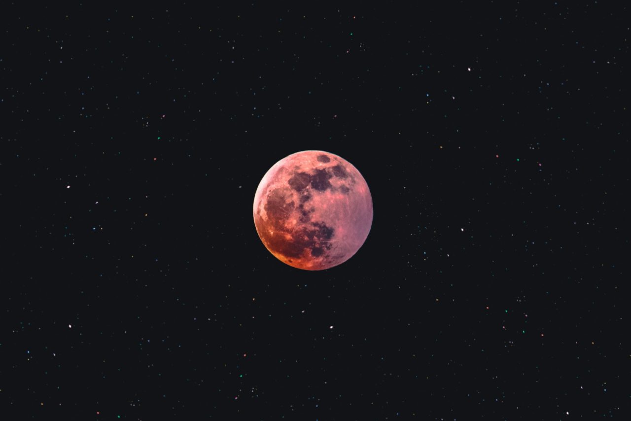 A pink moon against the blackness of space