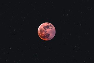A pink moon against the blackness of space