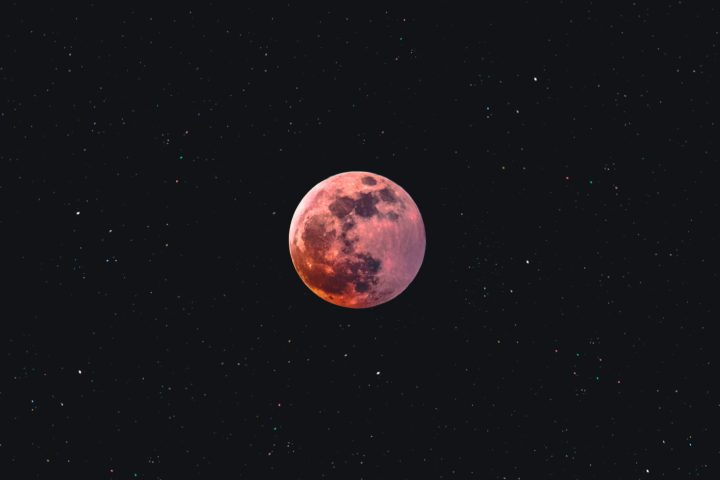 A pink moon against the blackness of space