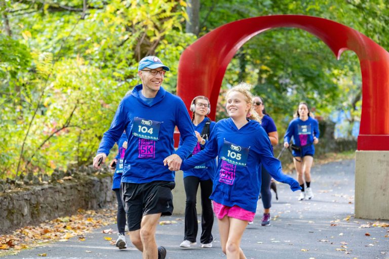 A father and daughter hold hands past the red arch sculpture during the Artful Dash 5K Run/Walk on the Karl Stirner Arts Trail in Easton, Pennsylvania.